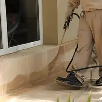 General pest control technician spraying exterior perimeter around a home in Peoria, IL