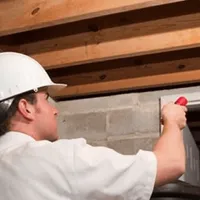Termite inspection technician checking a basement wall and framing for termite activity in Peoria, IL