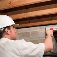 Termite inspection technician checking a basement wall and framing for termite activity in Peoria, IL